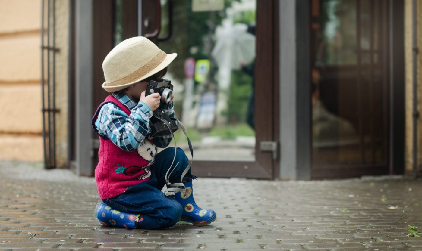 city break: boy kneeling on the pavement taking photos