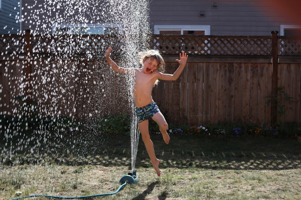 family activities - boy playing with sprinkler in garden