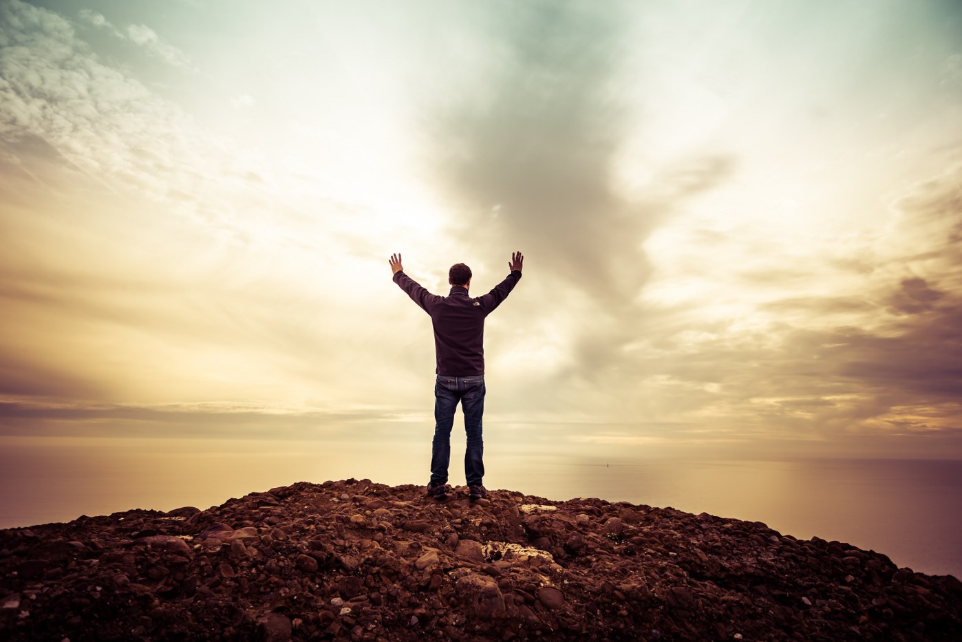 singles holidays over 40 - man on top of hill with arms in the air