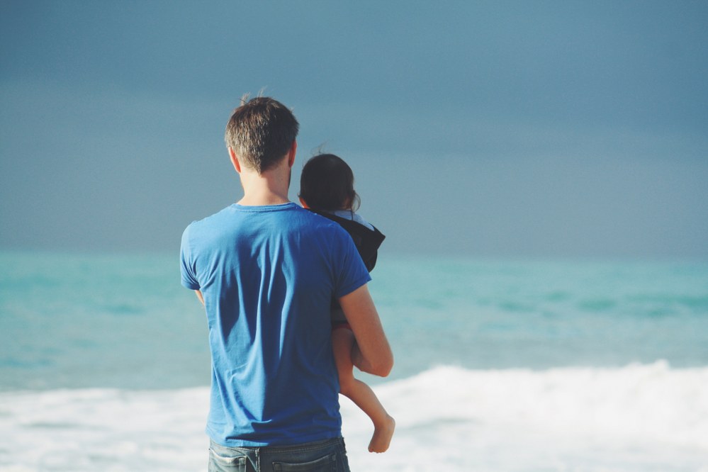 single dad and toddler with sea in background