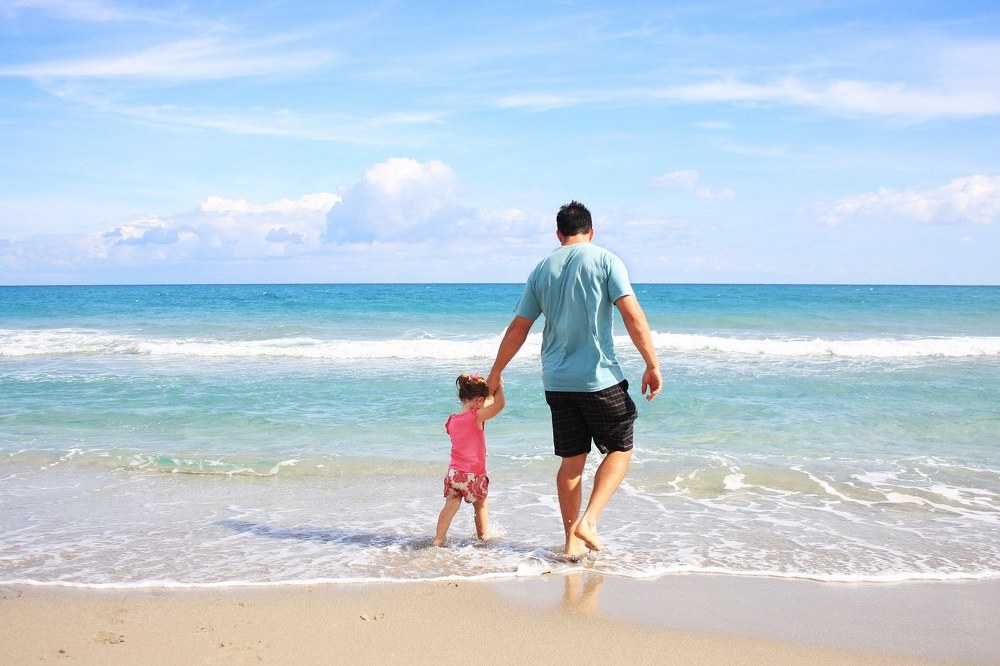single dad and daughter on beach holiday