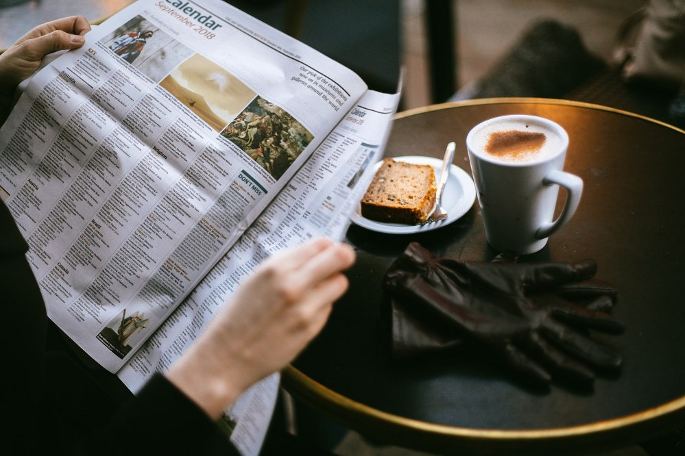 woman on solo travel reading paper and having breakfast