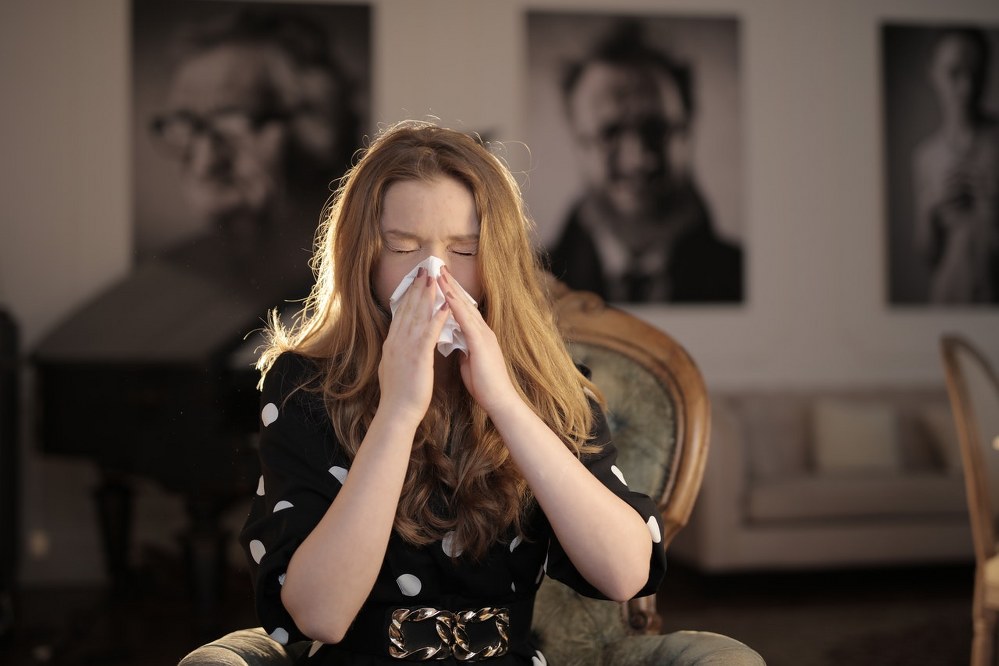 woman sneezing in tissue during coronavirus pandemic