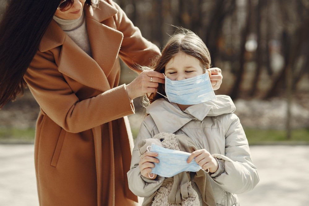 mother helping daughter with facemask during coronavirus