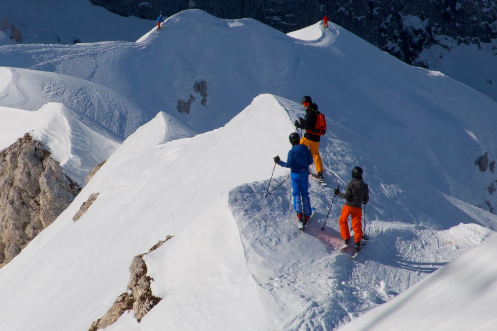 skiers on edge of steep slope