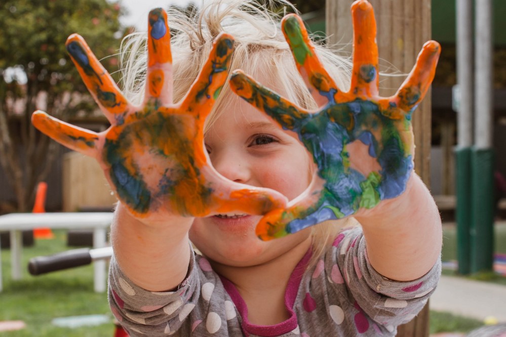 happy and confident young child with painted hands