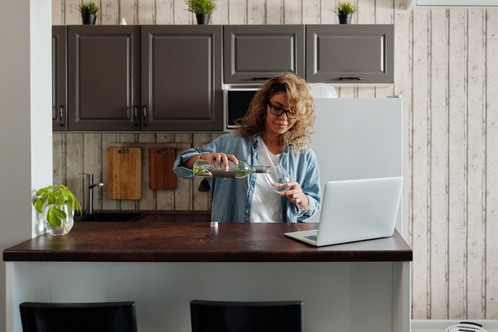 woman pouring wine in front of laptop