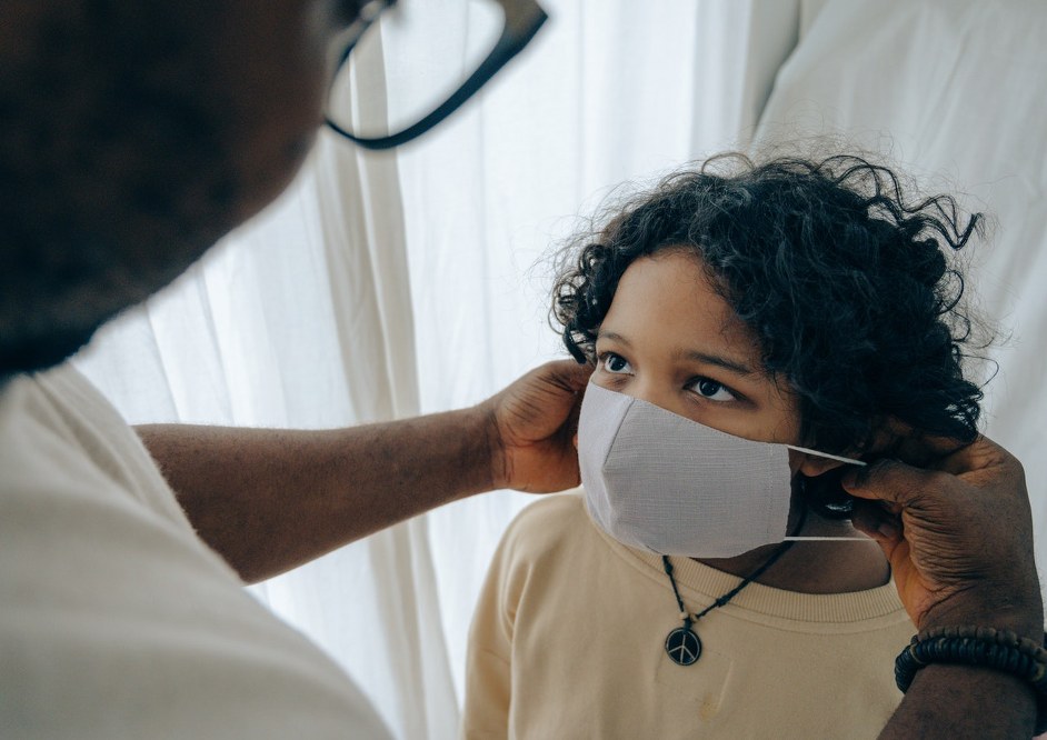 parent putting face mask on child - COVID 19