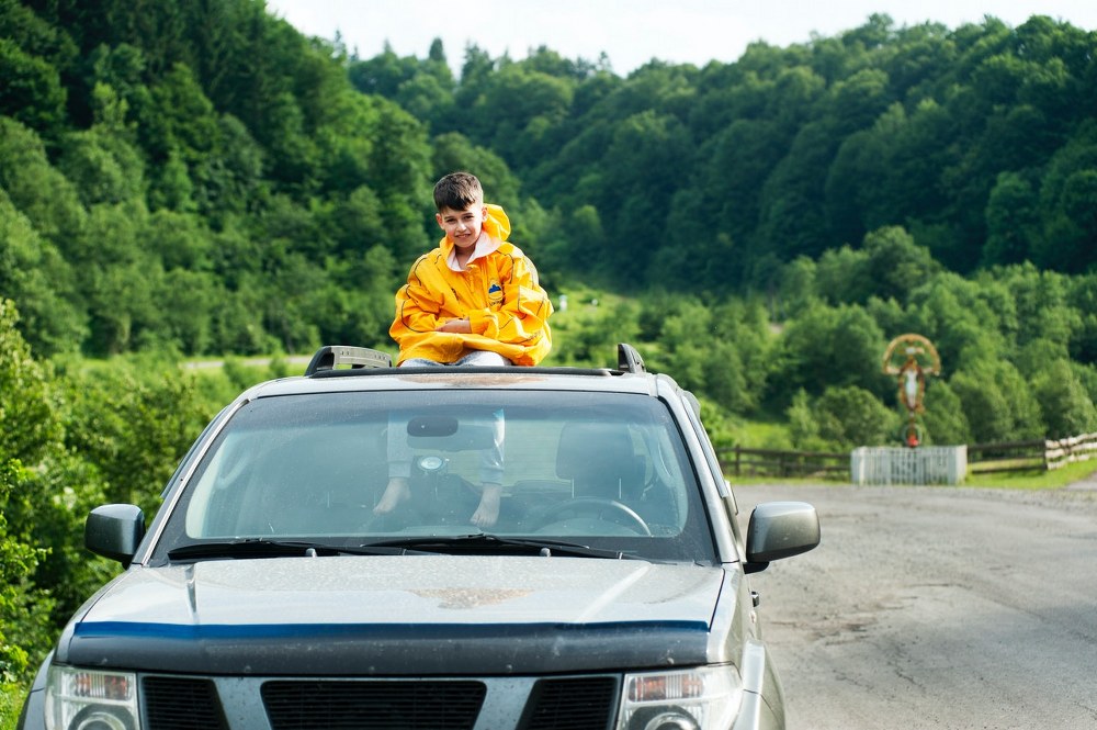 kid sitting on car rooftop