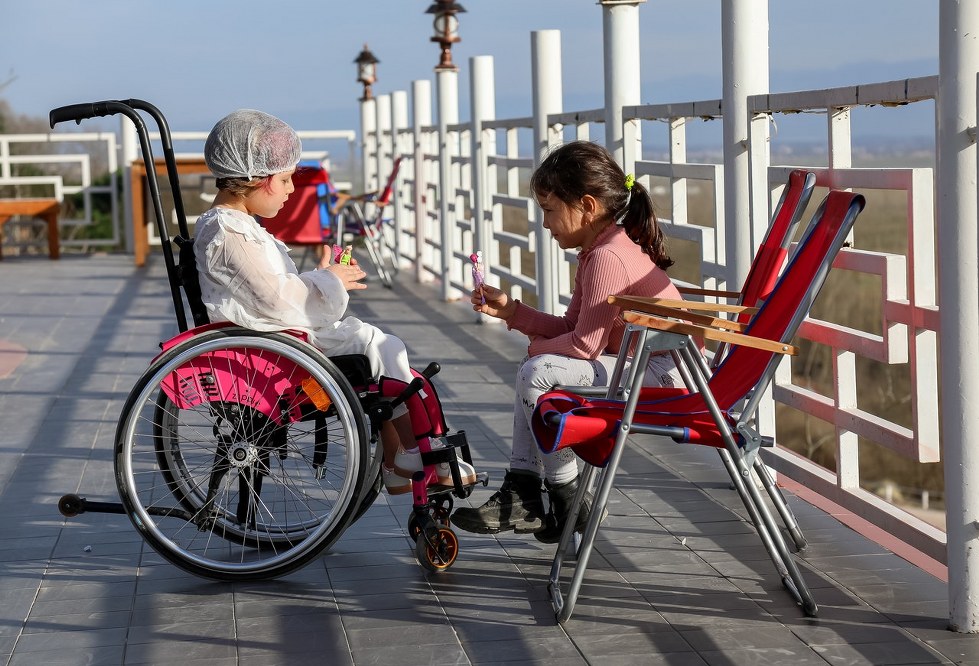 girl in wheelchair on holiday playing with sister