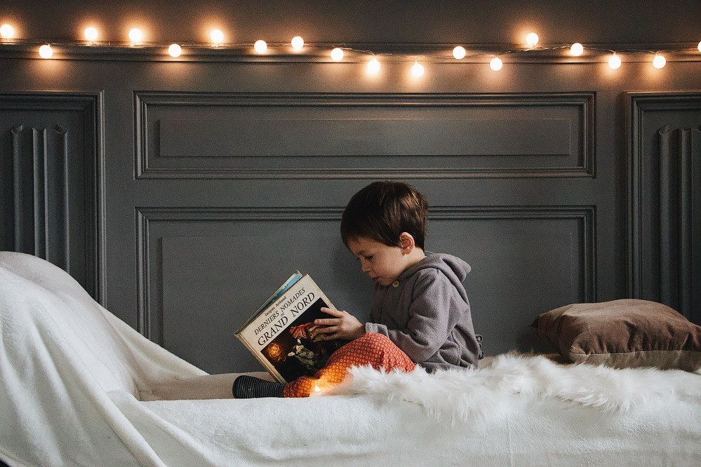 boy reading in bed with fairy lights