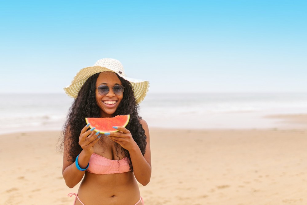 female solo traveller with water melon on beach