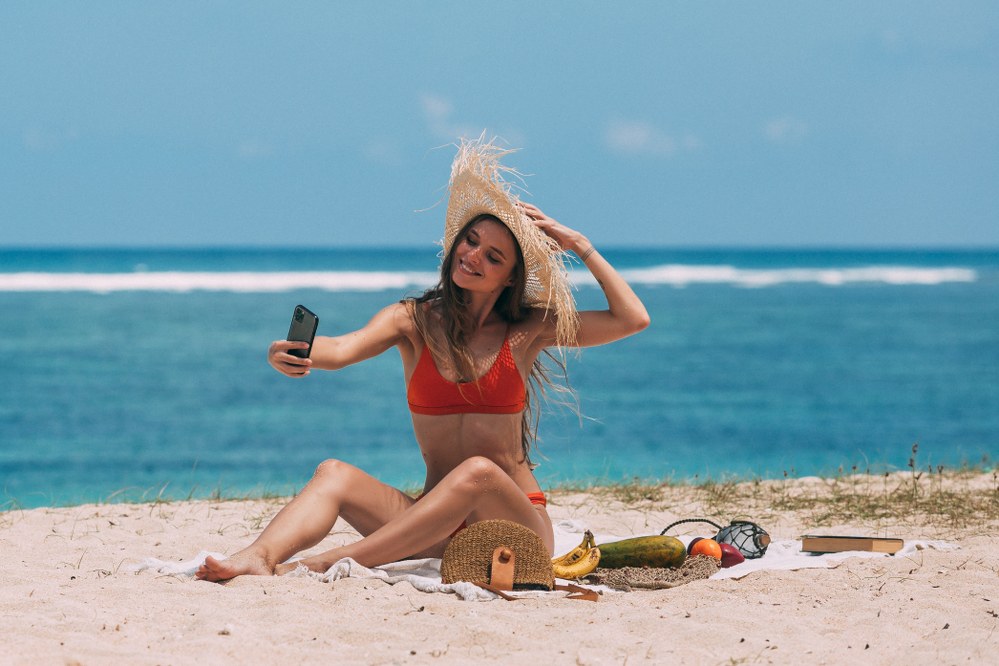 female solo traveller taking selfie on beach