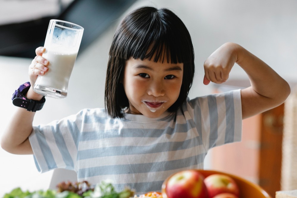 girl drinking milk and showing her muscles