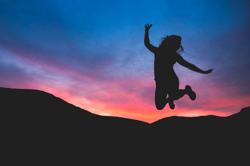 happy woman jumping in the air at dawn