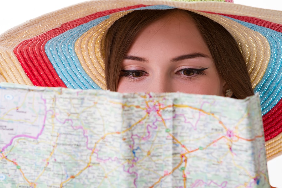 young girl wearing a sunhat reading map