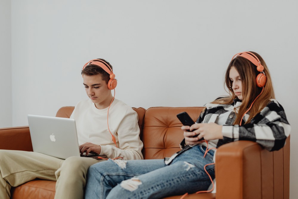 teenagers with laptop and mobile on sofa