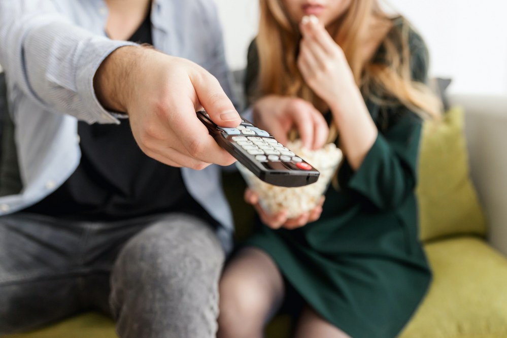 person holding remote control to start holiday movies