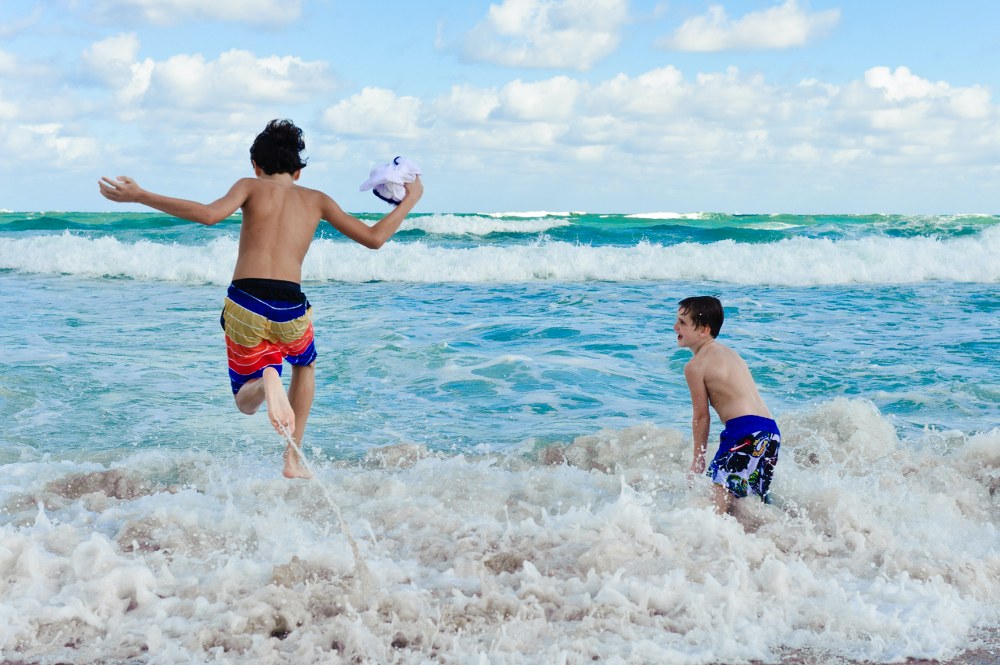 boys playing in the waves of the sea on holiday