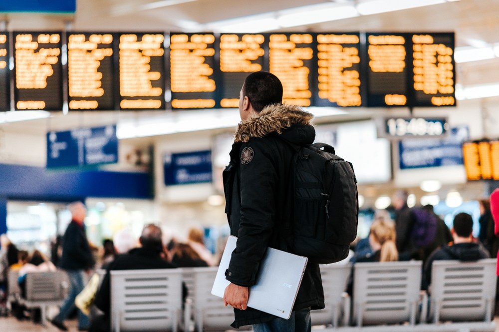 man in front of departures board at airport