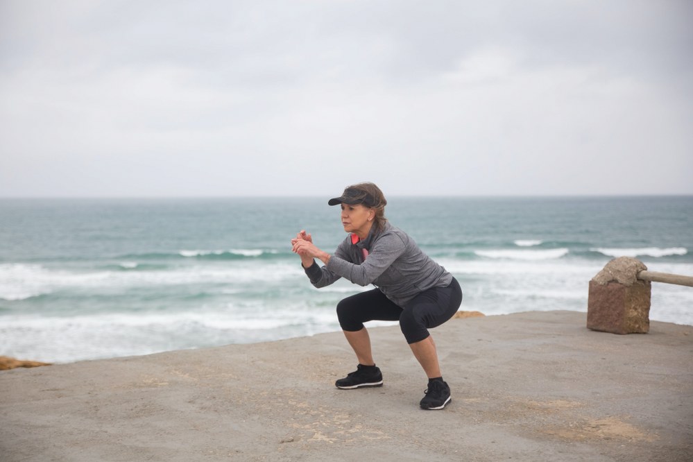 older woman exercising be the sea