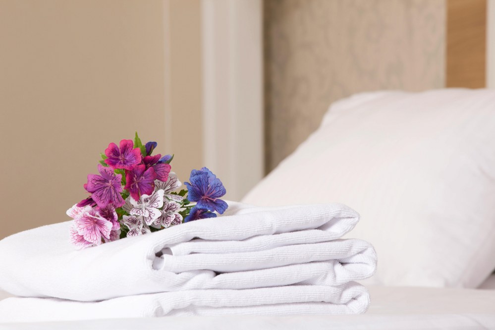 towels folded on hotel bed with flowers
