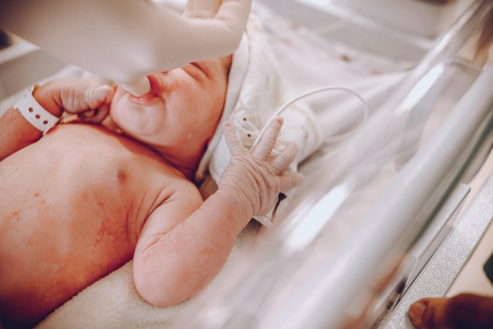 premature newborn baby sucking gloved finger