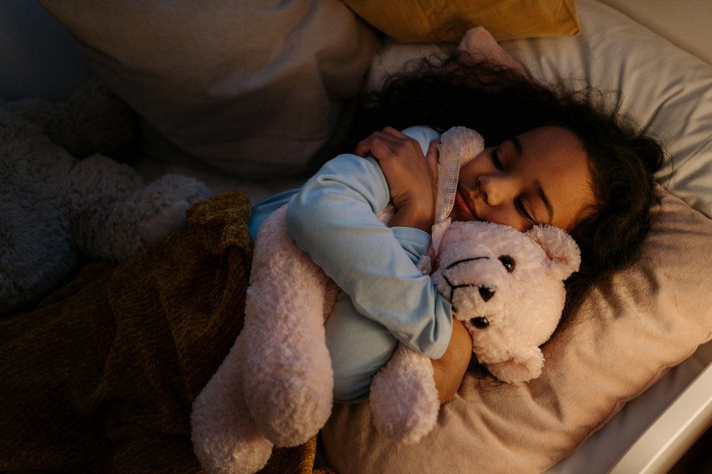 girl being comforted by teddies in bed