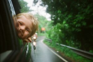 boy leaning out of the window on family road trip