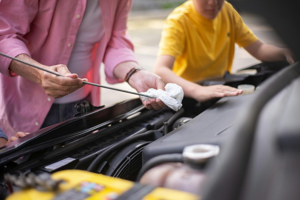man checking oil level in car for family road trips