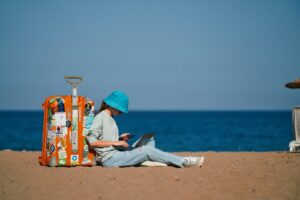 how to keep kids safe online: girl with laptop and mobile phone on the beach