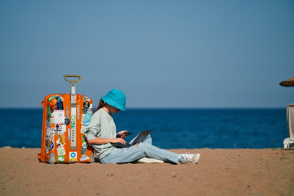 how to keep kids safe online: girl with laptop and mobile phone on the beach