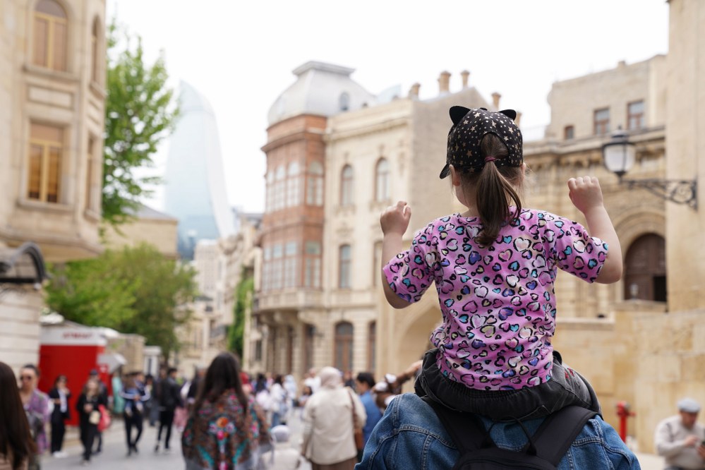 child travelling on shoulders of parent on holiday
