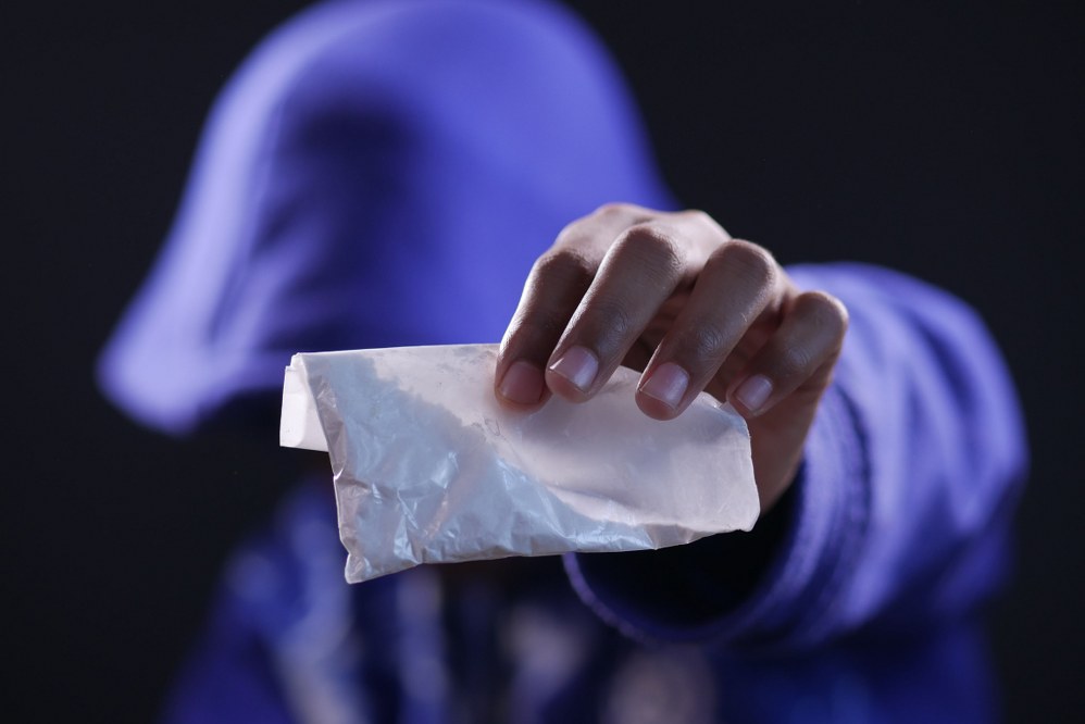 hooded man handing over drugs
