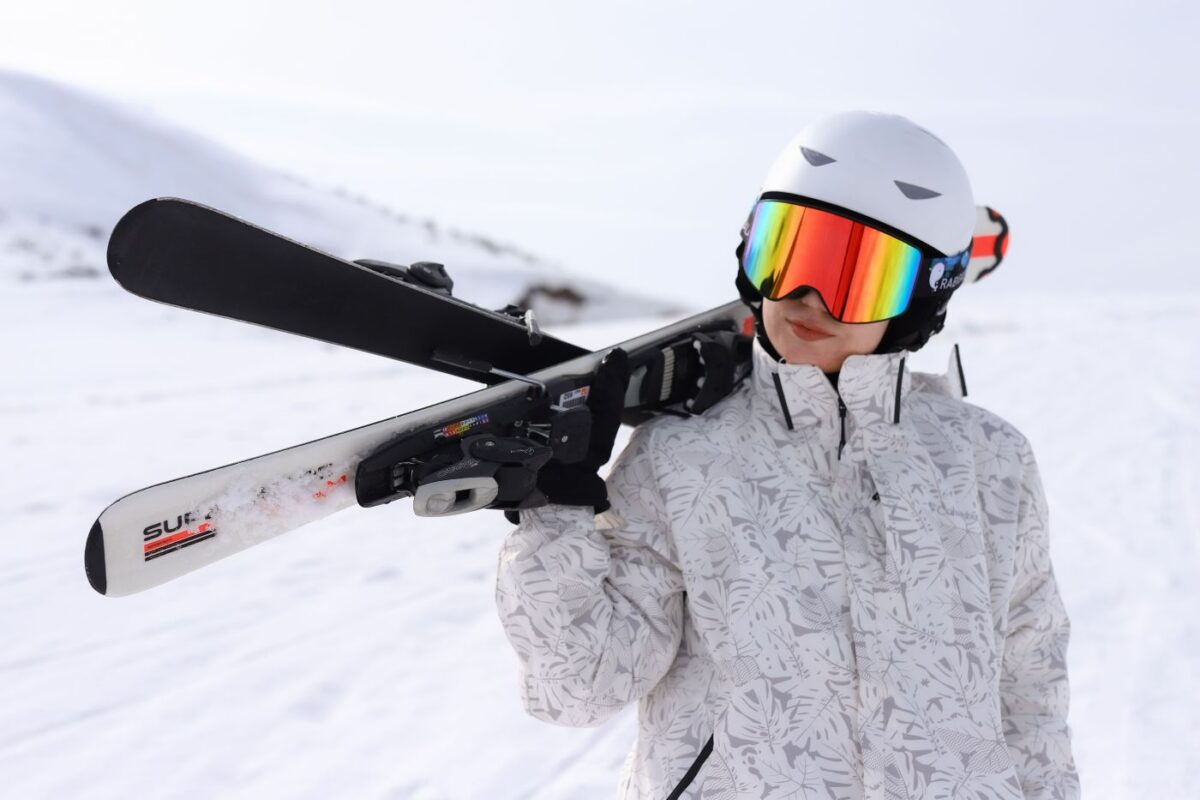 stylish looking teenager carrying skis on shoulder